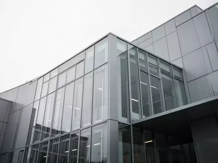 Moderne Fassade eines Bürogebäudes aus Glas und Stahl vor einem bewölkten Himmel. - Foto: über boerse-global.de