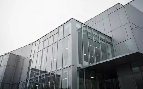 Moderne Fassade eines Bürogebäudes aus Glas und Stahl vor einem bewölkten Himmel. - Foto: über boerse-global.de