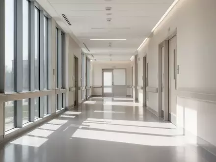 Ein minimalistischer, hell beleuchteter Krankenhausflur mit neutraler Architektur und langen Schatten auf dem Boden. - Foto: über boerse-global.de