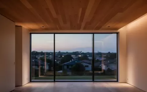 Ein minimalistisch gestalteter Wohnraum bei Dämmerung mit warmem Licht und Blick auf eine ruhige Wohngegend. - Foto: über boerse-global.de