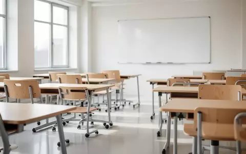 Ein heller, moderner Unterrichtsraum mit leeren Schultischen und großen Fenstern, der eine professionelle Lernumgebung darstellt. - Foto: über boerse-global.de