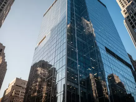 Moderne Glasfassade eines Bürogebäudes in einem Finanzviertel unter einem klaren blauen Himmel. - Foto: über boerse-global.de