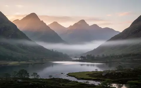 Eine neblige Berglandschaft in den britischen Highlands bei Sonnenaufgang, die Ruhe und Erholung symbolisiert. - Foto: über boerse-global.de