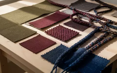 Verschiedene Textilproben und recycelte Materialien in gedeckten Farben auf einer hölzernen Werkbank. - Foto: über boerse-global.de