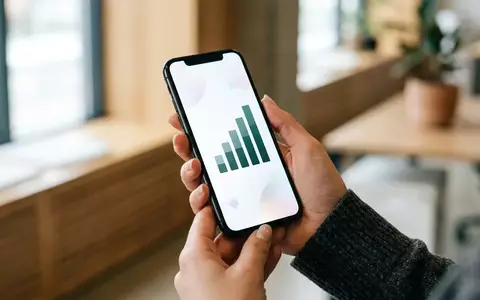 Nahaufnahme einer Hand, die ein Smartphone mit einer Finanz-App zeigt, die ein wachsendes Balkendiagramm anzeigt. - Foto: über boerse-global.de