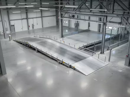 Leere, sterile Prüfhalle für Nutzfahrzeuge mit glattem Betonboden und industrieller Stahlarchitektur. - Foto: über boerse-global.de
