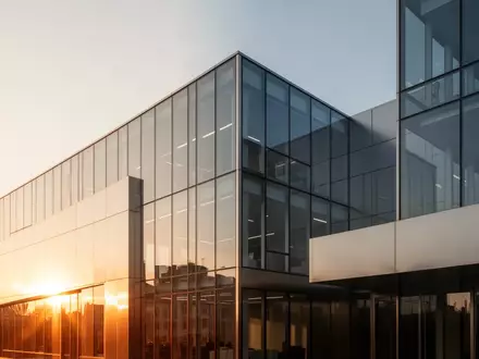 Ein modernes, minimalistisches Bürogebäude aus Glas und Stahl im goldenen Licht der Nachmittagssonne. - Foto: über boerse-global.de
