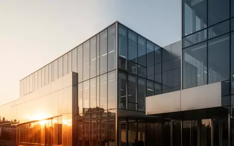Ein modernes, minimalistisches Bürogebäude aus Glas und Stahl im goldenen Licht der Nachmittagssonne. - Foto: über boerse-global.de