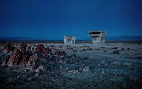 Eine weite, karge Wüstenlandschaft mit einem verlassenen Beobachtungsbunker in der Ferne bei Dämmerung. - Foto: über boerse-global.de