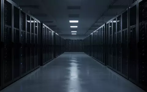 Ein weitläufiger, unbesetzter Serverraum mit dunklen Metallgehäusen in kühlem Licht, der die digitale Infrastruktur symbolisiert. - Foto: über boerse-global.de