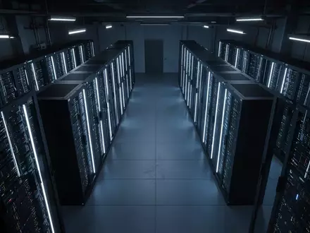 Ein dunkler, symmetrischer Serverraum mit blau beleuchteten Server-Racks in einer minimalistischen, industriellen Umgebung. - Foto: über boerse-global.de