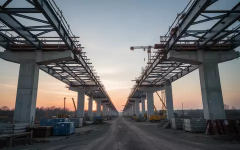 Eine Baustelle für eine Brücke mit Stahlträgern und Betonpfeilern in der Abenddämmerung. - Foto: über boerse-global.de