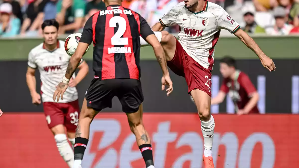 Leverkusens Facundo Medina (links) und Arijon Ibrahimovic vom FC Augsburg kämpfen um den Ball. - Bild: Harry Langer/dpa