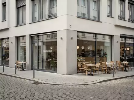 Ein ruhiges, modernes Straßenbild mit einem Café in einer deutschen Stadt bei Tageslicht, ohne Menschen oder Schilder. - Foto: über boerse-global.de