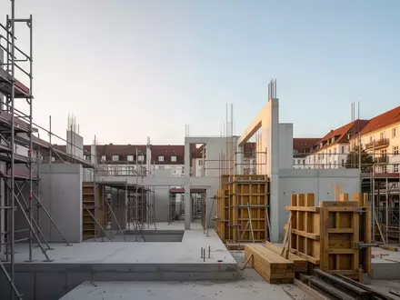 Eine moderne Baustelle mit Betonstrukturen und Gerüsten im Stadtteil Stühlinger bei Sonnenuntergang. - Foto: über boerse-global.de