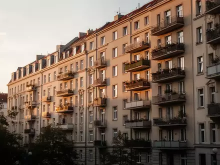 Ein mehrstöckiges Wohnhaus in Berlin bei goldenem Abendlicht, das die städtische Wohnsituation widerspiegelt. - Foto: über boerse-global.de