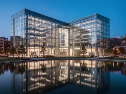 Moderne Glasarchitektur eines Bankgebäudes in Kansas City während der Dämmerung, gespiegelt in einem ruhigen Wasserbecken. - Foto: über boerse-global.de