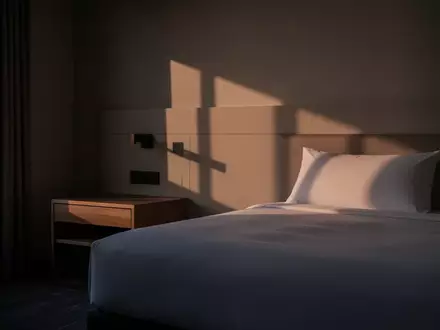 Ein minimalistisch eingerichtetes Hotelzimmer bei Dämmerung, das eine ruhige und private Atmosphäre vermittelt. - Foto: über boerse-global.de