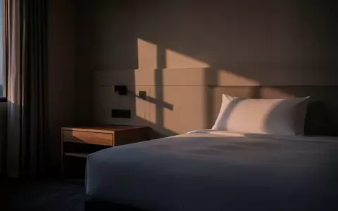 Ein minimalistisch eingerichtetes Hotelzimmer bei Dämmerung, das eine ruhige und private Atmosphäre vermittelt. - Foto: über boerse-global.de