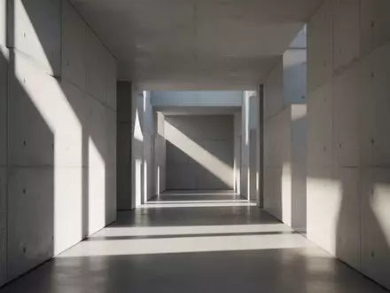 Ein minimalistischer, hell erleuchteter Flur mit geometrischen Schattenwürfen auf glatten Betonwänden. - Foto: über boerse-global.de