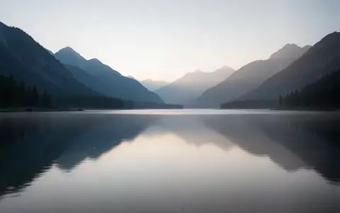 Eine ruhige Berglandschaft mit einem stillen See im sanften Licht der Morgendämmerung, die eine meditative Atmosphäre ausstrahlt. - Foto: über boerse-global.de
