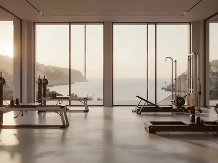 Ein minimalistisches, lichtdurchflutetes Fitnessstudio mit hochwertigen Trainingsgeräten und Blick auf eine Küstenlandschaft. - Foto: über boerse-global.de