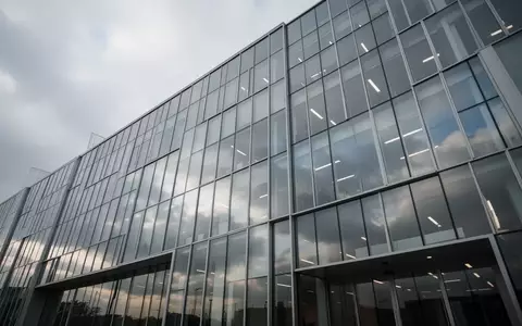 Moderne Glasfassade eines Bürogebäudes bei bewölktem Himmel. - Foto: über boerse-global.de