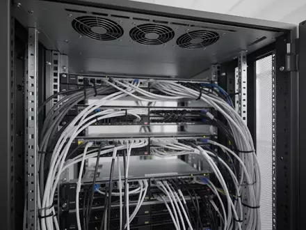Eine Nahaufnahme von geordneten Kabeln und Kühlkomponenten in einem modernen Serverschrank. - Foto: über boerse-global.de