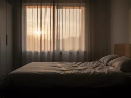Ein minimalistisch eingerichtetes Schlafzimmer in der Morgendämmerung mit weichem, natürlichem Licht. - Foto: über boerse-global.de