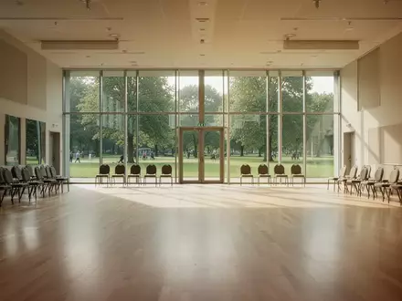 Ein heller, leerer Tanzsaal mit Parkettboden und großen Fenstern, die den Blick in einen grünen Park freigeben. - Foto: über boerse-global.de