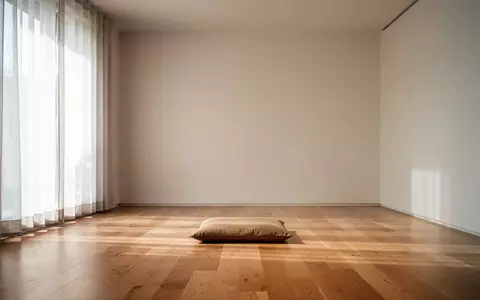 Ein minimalistischer, lichtdurchfluteter Raum mit einem leeren Sitzkissen auf einem Holzboden zur Meditation. - Foto: über boerse-global.de
