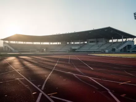 Eine leere Laufbahn in einem Stadion bei Sonnenaufgang, die Ruhe und den Prozess der sportlichen Rehabilitation symbolisiert. - Foto: über boerse-global.de