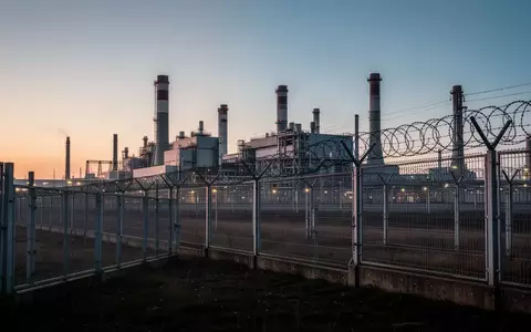 Ein Sicherheitszaun eines Kraftwerksgeländes in der Abenddämmerung als Symbol für den Schutz kritischer Infrastrukturen. - Foto: über boerse-global.de