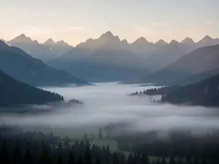 Eine weite, neblige Berglandschaft in der Morgendämmerung, die Ruhe und Besonnenheit ausstrahlt. - Foto: über boerse-global.de