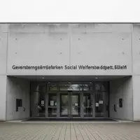 Eingangsbereich eines Jobcenters mit minimalistischer Betonarchitektur bei Tageslicht. - Foto: über boerse-global.de