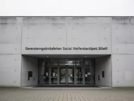 Eingangsbereich eines Jobcenters mit minimalistischer Betonarchitektur bei Tageslicht. - Foto: über boerse-global.de
