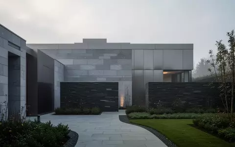 Architekturaufnahme eines modernen Krematoriumsgebäudes mit grauer Steinfassade und schlichten geometrischen Formen. - Foto: über boerse-global.de