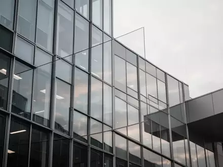 Moderne Glasfassade eines Bürogebäudes bei bewölktem Himmel als Symbol für arbeitsrechtliche Konflikte und Mitbestimmung. - Foto: über boerse-global.de