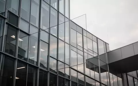 Moderne Glasfassade eines Bürogebäudes bei bewölktem Himmel als Symbol für arbeitsrechtliche Konflikte und Mitbestimmung. - Foto: über boerse-global.de