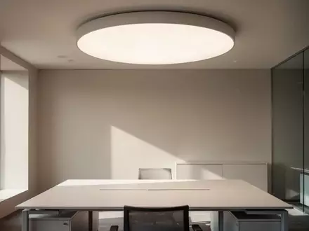 Ein minimalistisch gestalteter, heller Arbeitsplatz mit einer modernen, runden Deckenleuchte, die für natürliches Licht sorgt. - Foto: über boerse-global.de
