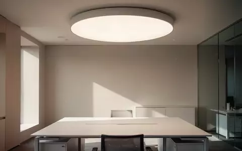 Ein minimalistisch gestalteter, heller Arbeitsplatz mit einer modernen, runden Deckenleuchte, die für natürliches Licht sorgt. - Foto: über boerse-global.de