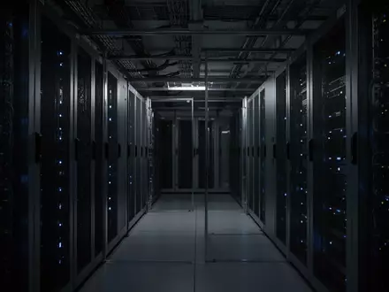 Minimalistische, dunkle Serverraum-Infrastruktur mit blau beleuchteten Racks und industrieller Ästhetik. - Foto: über boerse-global.de