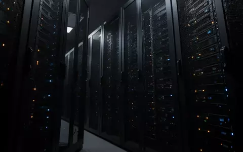 Dunkler Serverraum mit schlichten, metallischen Server-Racks und dezenten Statusleuchten in einer industriellen Umgebung. - Foto: über boerse-global.de
