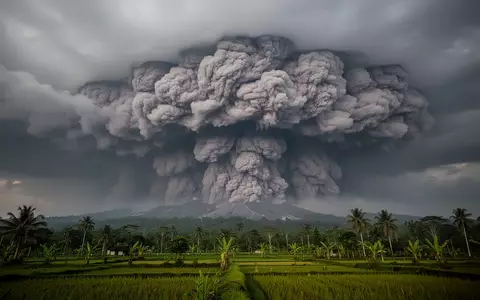 Eine graue Vulkanaschewolke über einer indonesischen Landschaft bei bewölktem Himmel. - Foto: über boerse-global.de
