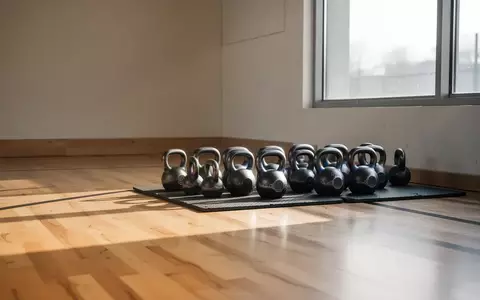Ein heller, minimalistisch eingerichteter Fitnessraum mit hochwertigen Kettlebells auf einem Bodenbelag in natürlichem Licht. - Foto: über boerse-global.de