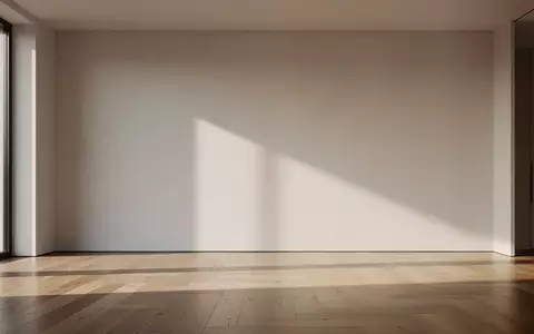 Ein minimalistisches, modernes Wohnzimmer mit leerer Wand und sanftem Lichteinfall. - Foto: über boerse-global.de