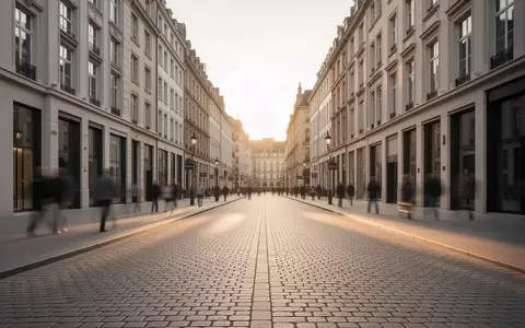 Eine leere, historische europäische Stadtstraße bei Sonnenuntergang mit moderner Architektur im Hintergrund. - Foto: über boerse-global.de
