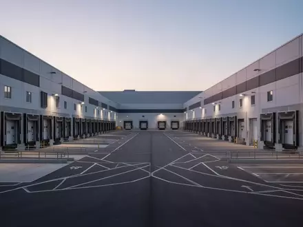 Ein modernes Logistikzentrum bei Dämmerung mit leeren Laderampen und weitläufigem Industriegelände. - Foto: über boerse-global.de
