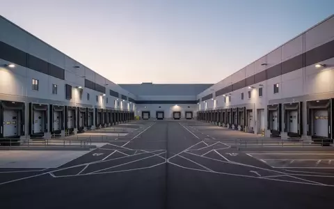 Ein modernes Logistikzentrum bei Dämmerung mit leeren Laderampen und weitläufigem Industriegelände. - Foto: über boerse-global.de