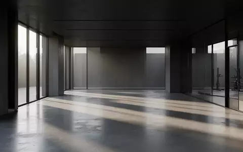 Ein leerer, modern gestalteter Fitnessraum mit poliertem Betonboden und großen Fensterfronten, die natürliches Licht einlassen. - Foto: über boerse-global.de